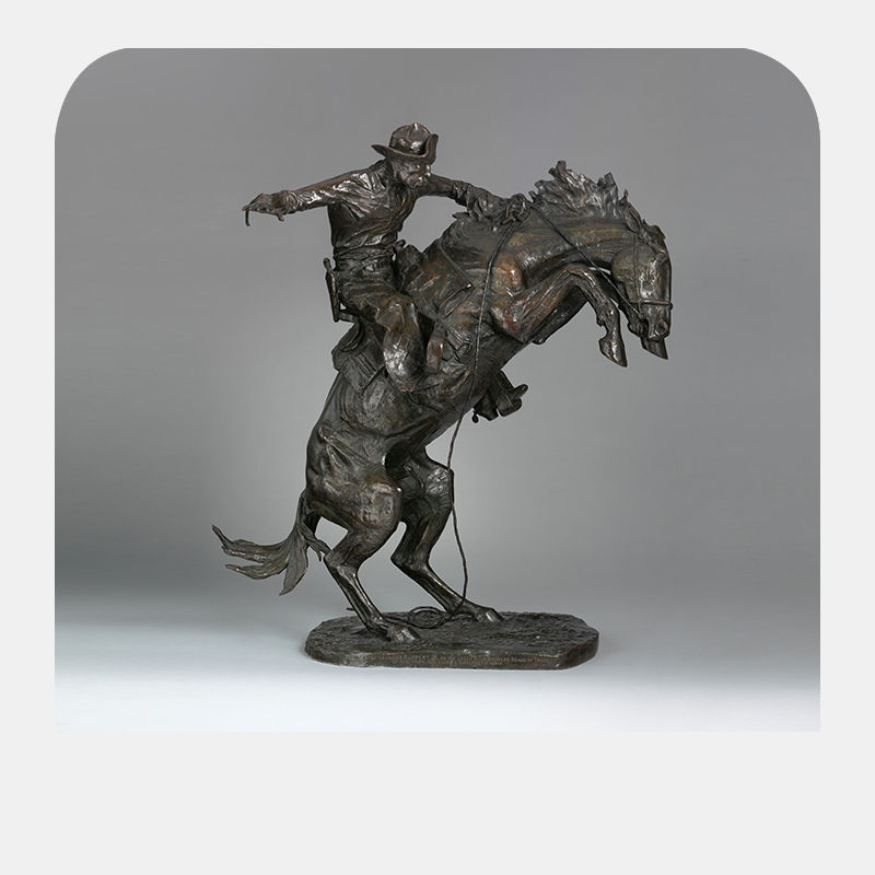 Bronze sculpture of a man on the back of a horse that stands on its hind legs.